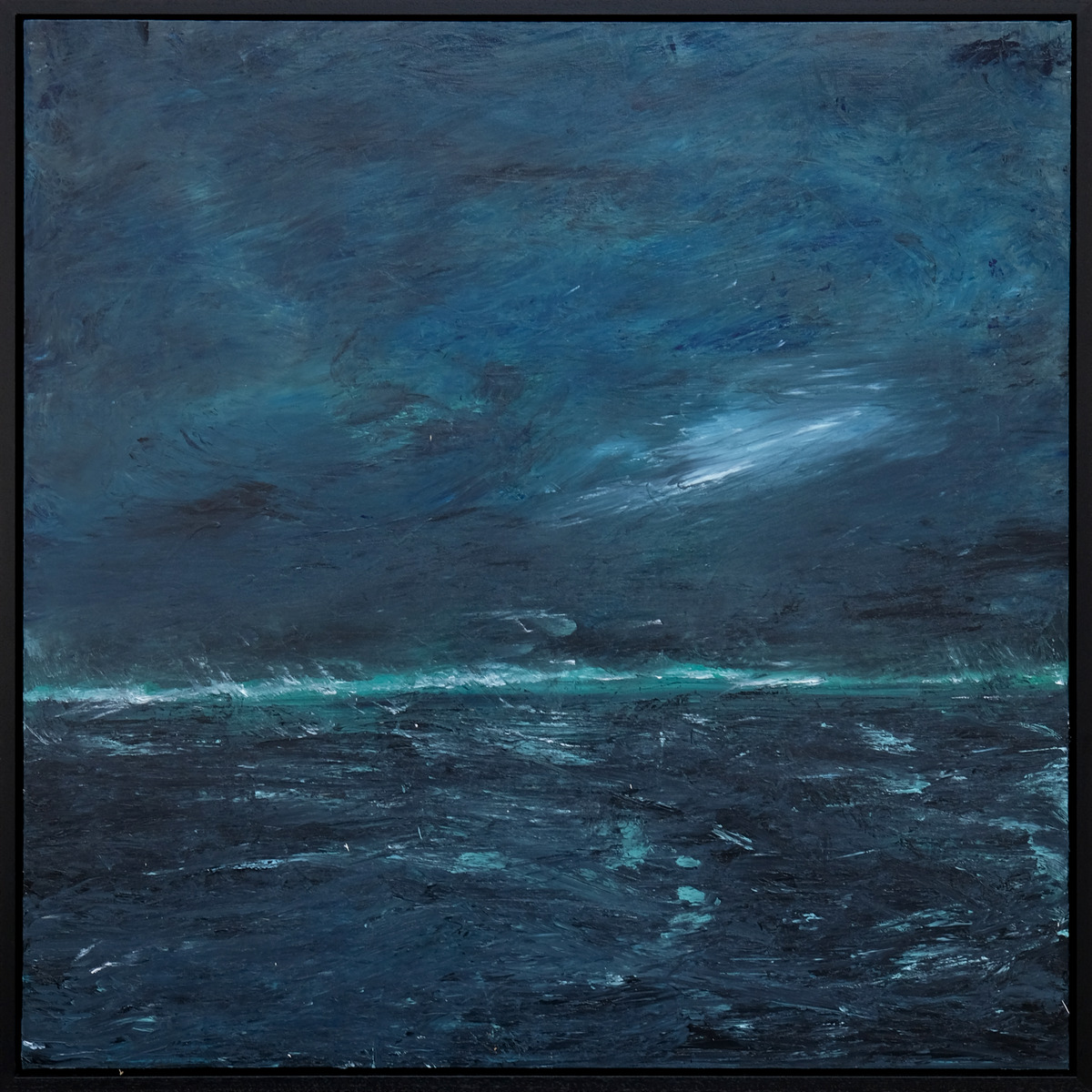 A dark blue-grey sky meets a dark sea at a narrow turquoise-green horizon, with pale wave marks across the water, presented in a black frame.