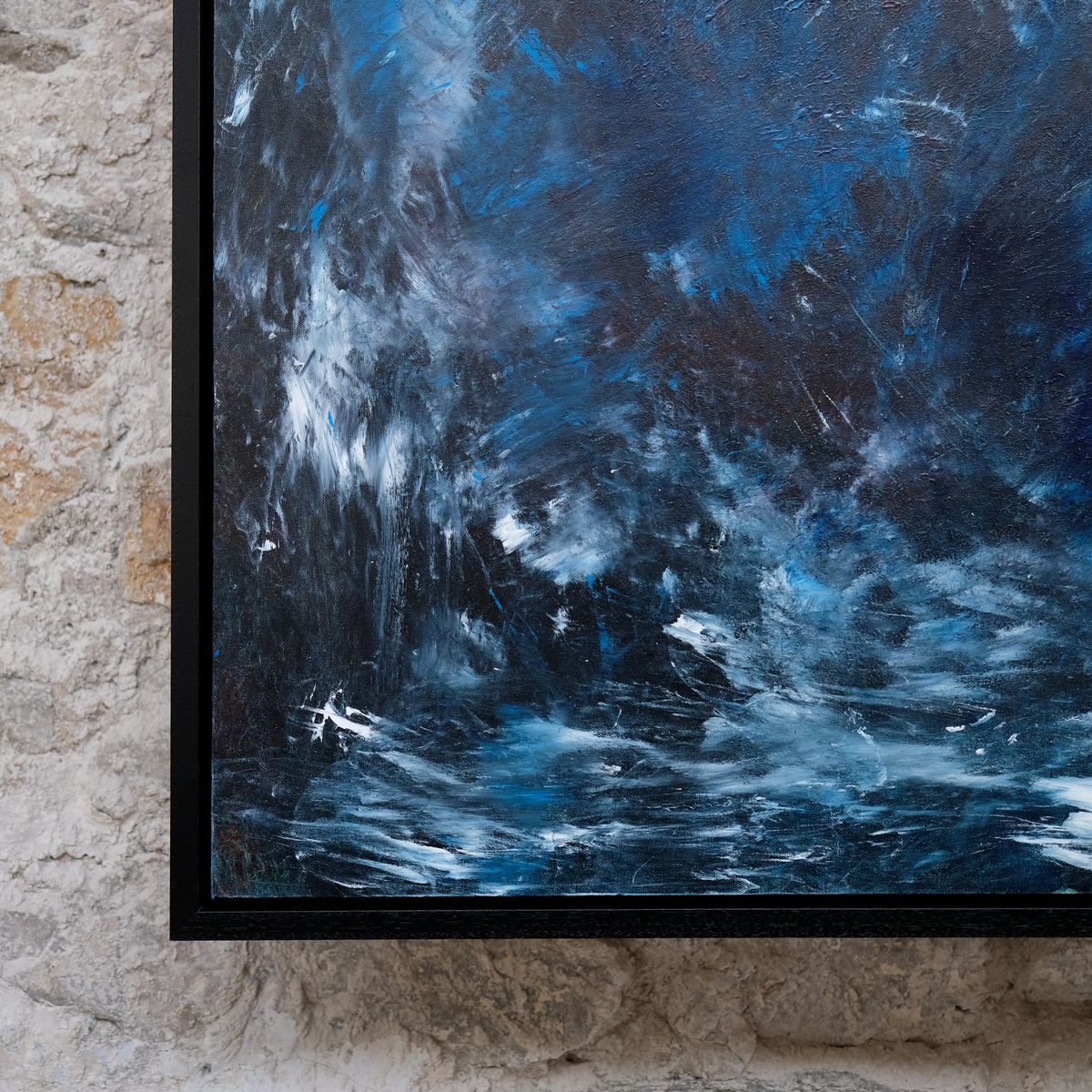Close-up of the lower-left corner of Wildwater, showing textured blue paint and white marks beside the black frame.