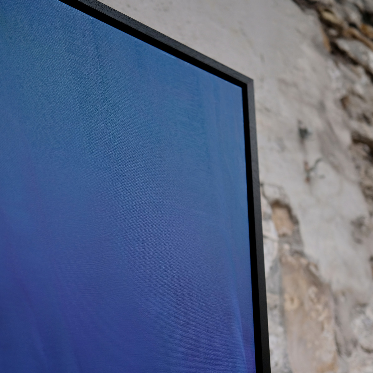 Angled close-up of the upper-right corner of The Long Blue, showing blue and violet painted canvas, visible canvas weave and the black frame.