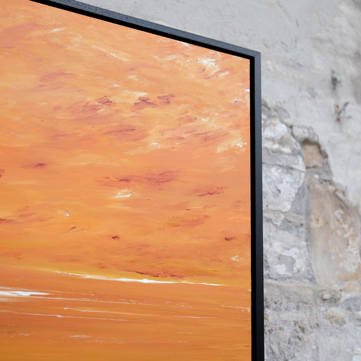 Angled close-up of the upper-right corner of The Burning Hour, showing orange painted sky, rust-red and pale marks, canvas texture and the black frame.