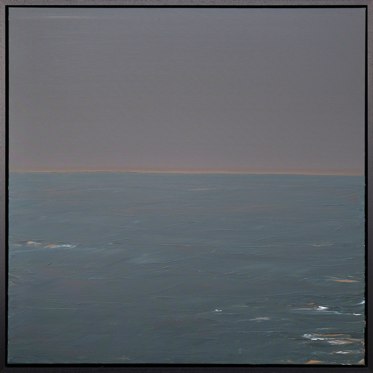A seascape with a muted grey-violet sky, a narrow warm horizon and blue-green water with small pale highlights in a black frame.