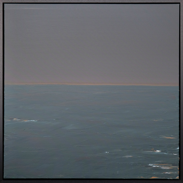 A seascape with a muted grey-violet sky, a narrow warm horizon and blue-green water with small pale highlights in a black frame.