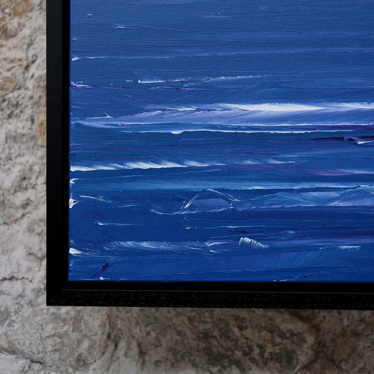 Close-up of the lower-left corner of The Long Blue, showing white and violet wave marks across deep blue water, canvas texture and the black frame.