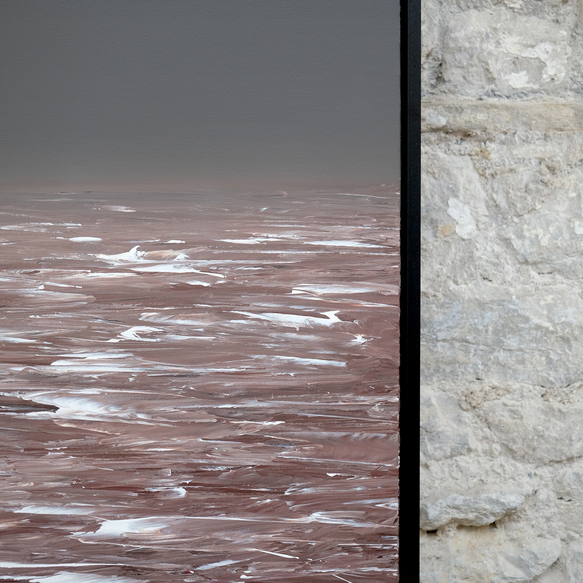 Detail of Rosewake showing a grey sky above muted rose-brown water with broad white wave marks beside the right edge of the black frame.