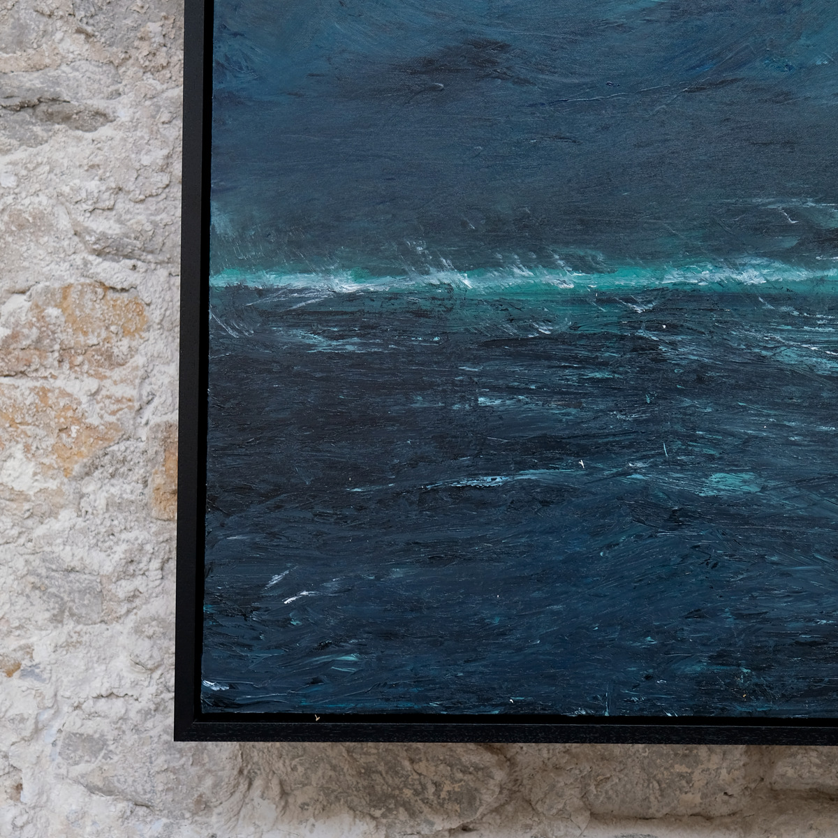 Close-up of the lower-left corner of A Thread of Light, showing textured dark blue paint, a turquoise-green horizon and pale wave marks beside the black frame.