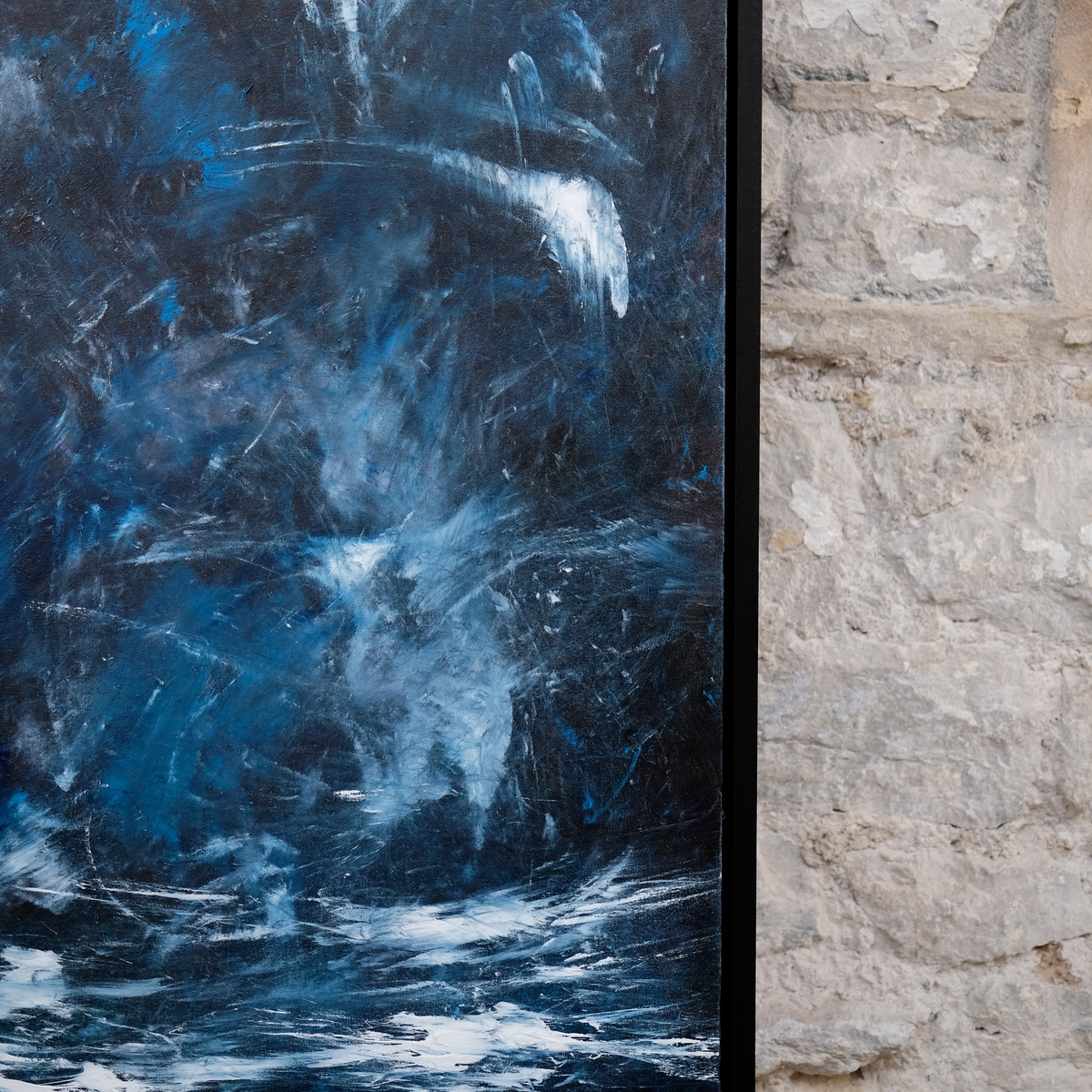 Detail of Wildwater showing pale blue and white marks across deep blue and charcoal paint beside the right edge of the black frame.
