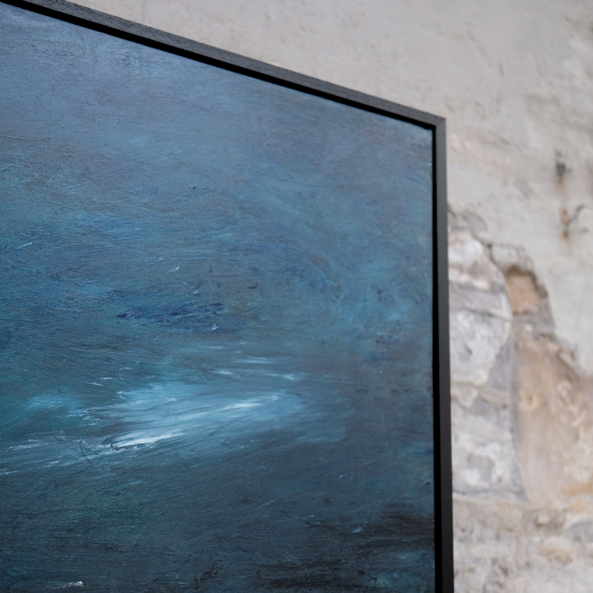 Angled close-up of the upper-right corner of A Thread of Light, showing blue-grey sky, pale sweeping marks, canvas texture and the black frame.