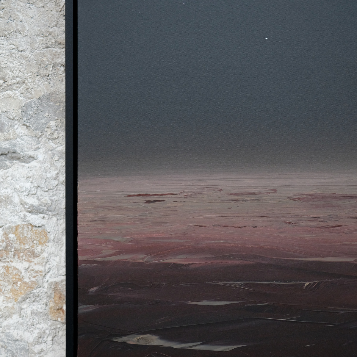 Detail of Afterlight showing the rose-coloured horizon, dark waves and small pale points in the sky beside the black frame.