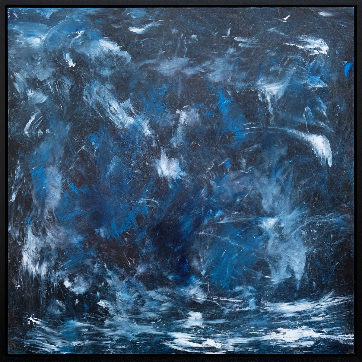 A seascape in deep blue, charcoal and pale blue, with sweeping white marks across a textured surface, presented in a black frame.