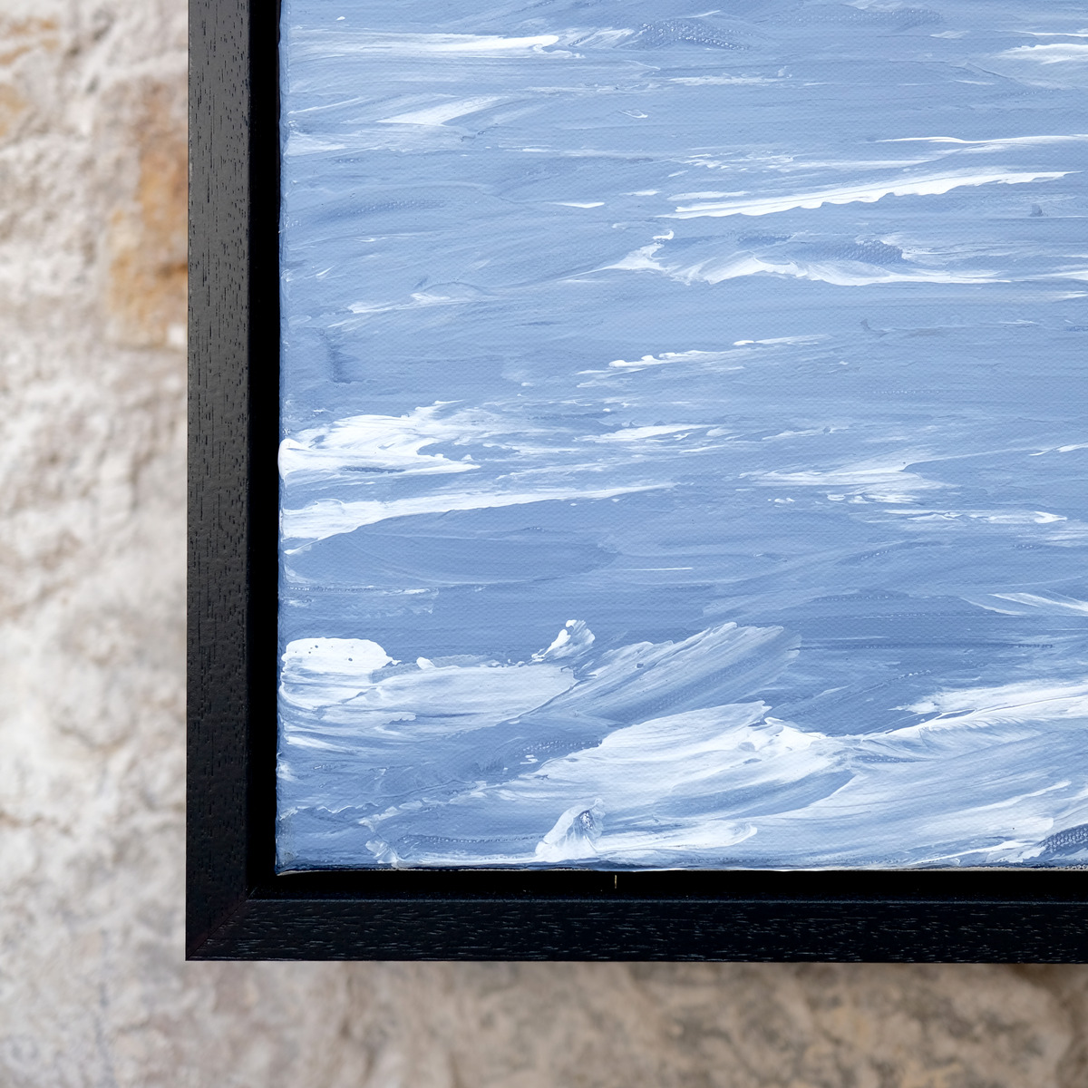 Close-up of the lower-left corner of Silver Unrest, with raised white wave crests across pale blue water beside the black frame.