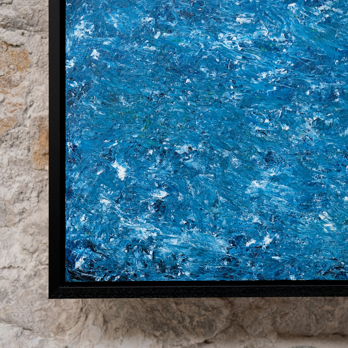 Close-up of the lower-left corner of A Thousand Tides, showing textured bright blue and turquoise paint with dark blue and white marks beside the black frame.