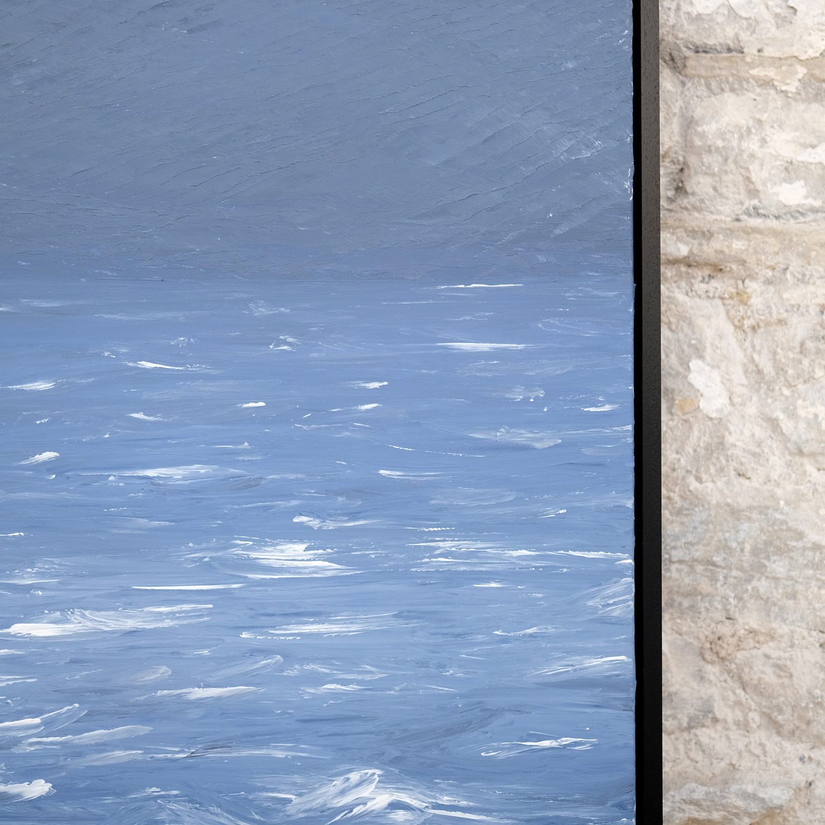 Detail of Silver Unrest showing textured pale blue sky and water, bright white wave marks and the right edge of the black frame.